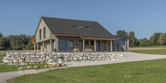 Neubau Wohnhaus mit wunderschönen Veranda im Amerikanischen-Style, Truberholz Wände sind sichtbar (mit Holzdübel sichtbar), das komplette Haus besteht aus Holz (es wurden keine Fermacel-Platten verwendet), Aussenschalung liegend - vorvergraut, ohne Kellergeschoss, dafür mit Garagenanbau direkt am Wohnhaus, das Haus ist ein Wohnhaus von einem Landwirtschaftlichen Betrieb, deshalb die integrierte Nasszone (Nassraum), der Badezimmerboden ist ein Massivholzboden aus Fichte (keine Fliessen) 