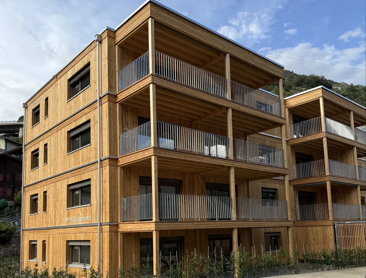 Mehrfamilienhaus in moderner Holzbauweise mit vier Geschossen, grosszügigen Balkonen und Holzfassade.