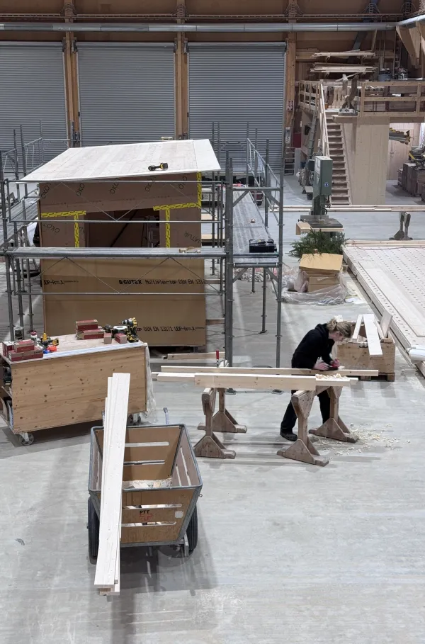 Blick in die Produktionshalle der Zimmerei Hirschi: Ein vorgefertigtes Holzmodul steht im Zentrum der Werkstatt, umgeben von Maschinen, Werkbänken und Holzbauelementen. Die industrielle Vorfertigung zeigt präzise Holzbauarbeit unter kontrollierten Bedingungen.