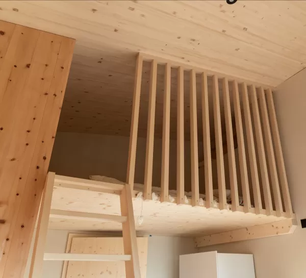 Truberholz Einfamilienhaus mit integrierter Arven-Täfer Wand. Schlafzimmer mit integrierter Dusche und Waschtisch. In der Dusche ist ein Brettstappel-Decke und der Boden ist aus ein Eschen Riemenboden. Die Wände sind Truberholz sichtbar. Die Decke ist leicht in der Dachschräge und ist eine Massivholzplatte. In der Wohnstube ist ein Cheminée mit Sitzoffen/Sitzbank.